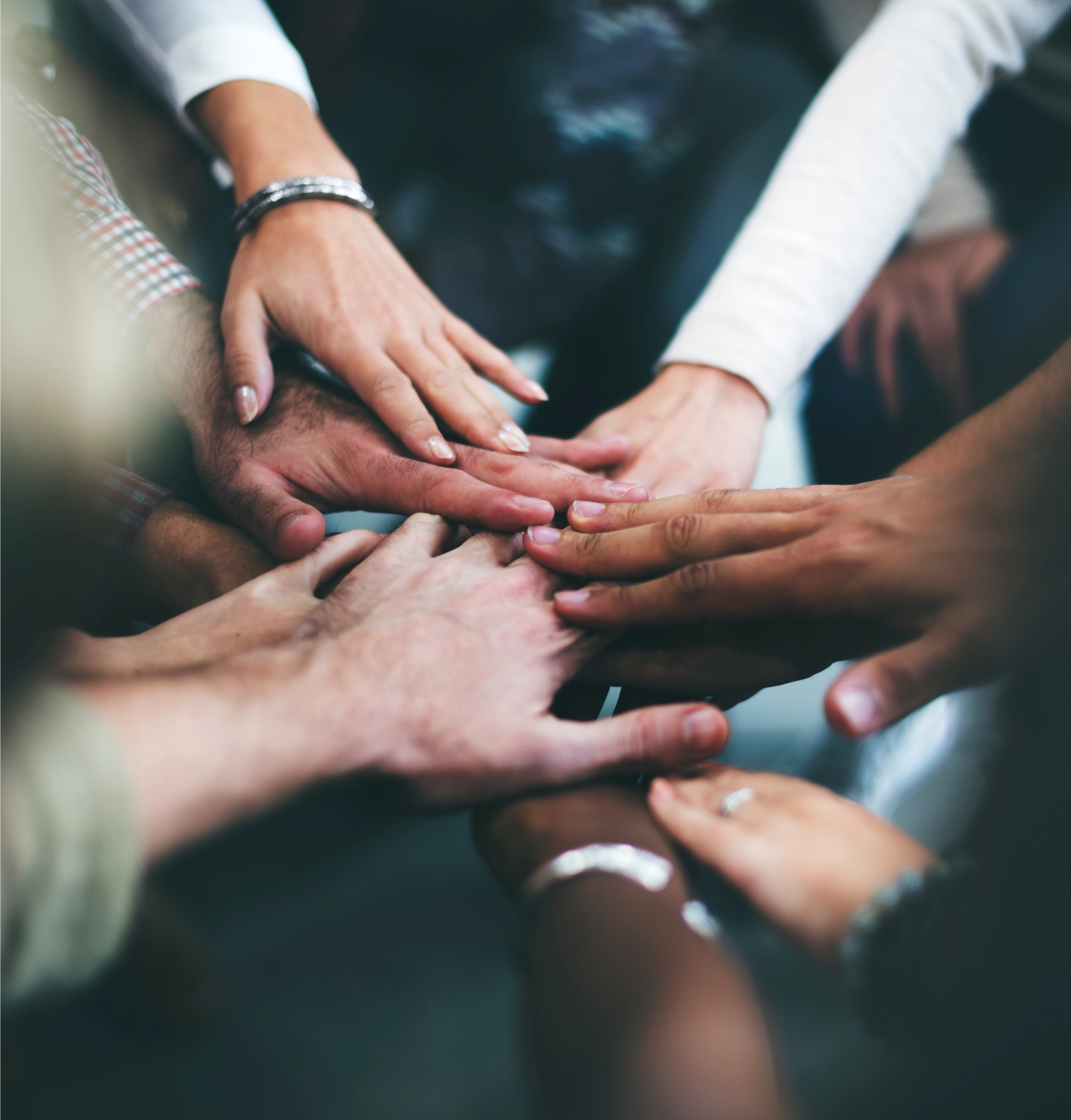 A group of Tonic team members with their hands stacked in a circle, symbolizing unity and collaboration.