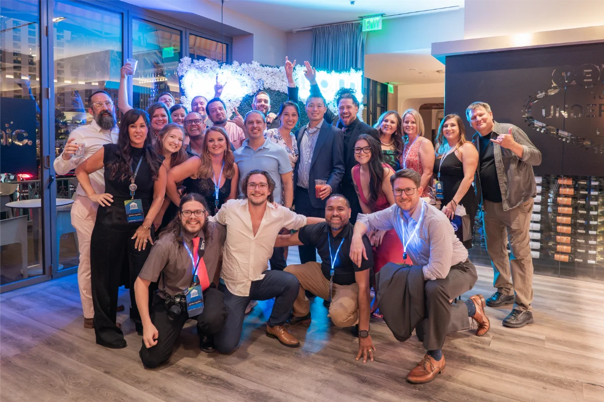 A group of Tonic employees smiling and waving at the camera at RetailNOW 2024.