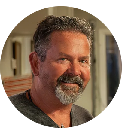 Morgan, owner of Brass Monkey, stands smiling in front of their bar.